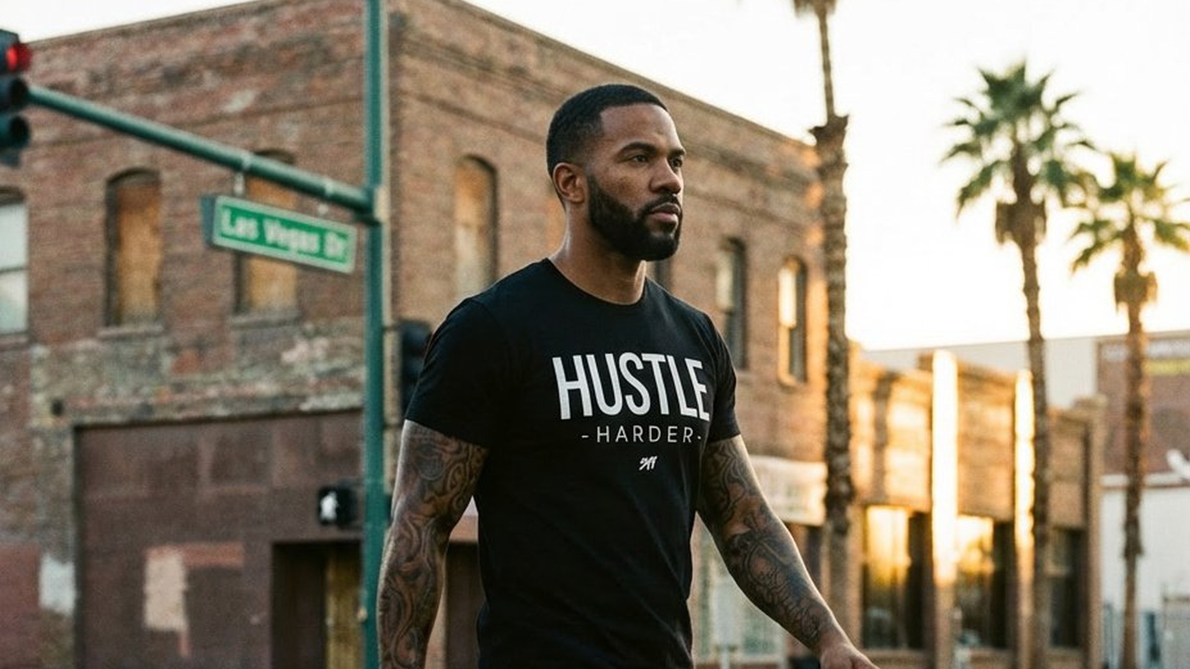 Wearing the Hustle Harder tee, mid-stride across a downtown Las Vegas crosswalk at golden hour, Las Vegas Drive street sign visible
